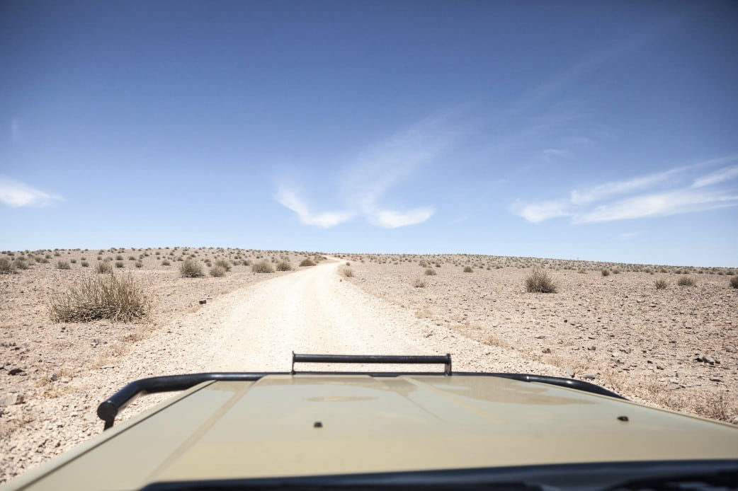 Blick über die Motorhaube auf eine Schotterpiste während einer Namibia-Selbstfahrerreise
