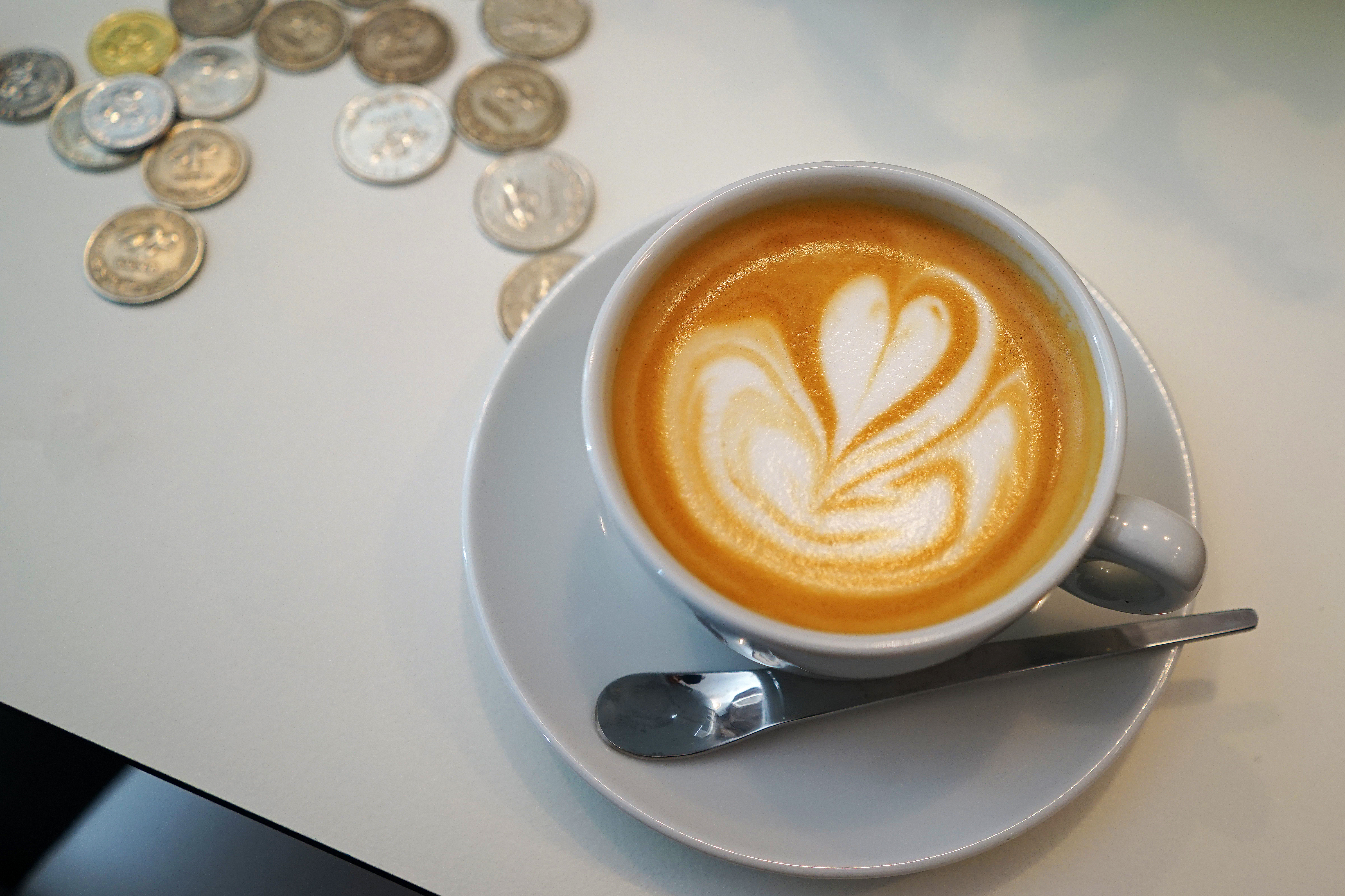 Close up ceramic cup of hot latte coffee and Croatian Kuna coins