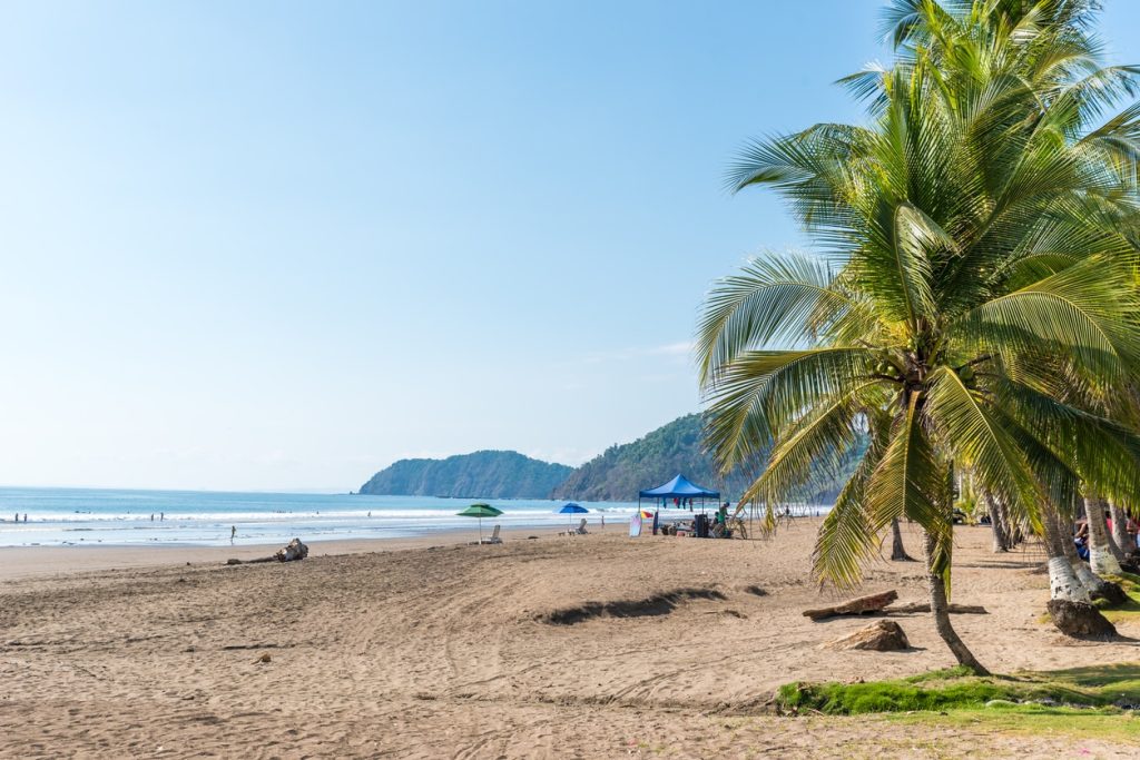 tropischer Strand mit Palmen, Felsformationen und Meer in Costa Rica