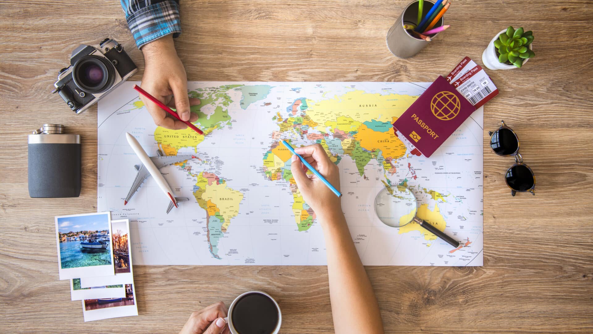 Zwei Personen arbeiten an einer Karte und planen eine Reise; Reiseinformationen auf dem Desktop.
