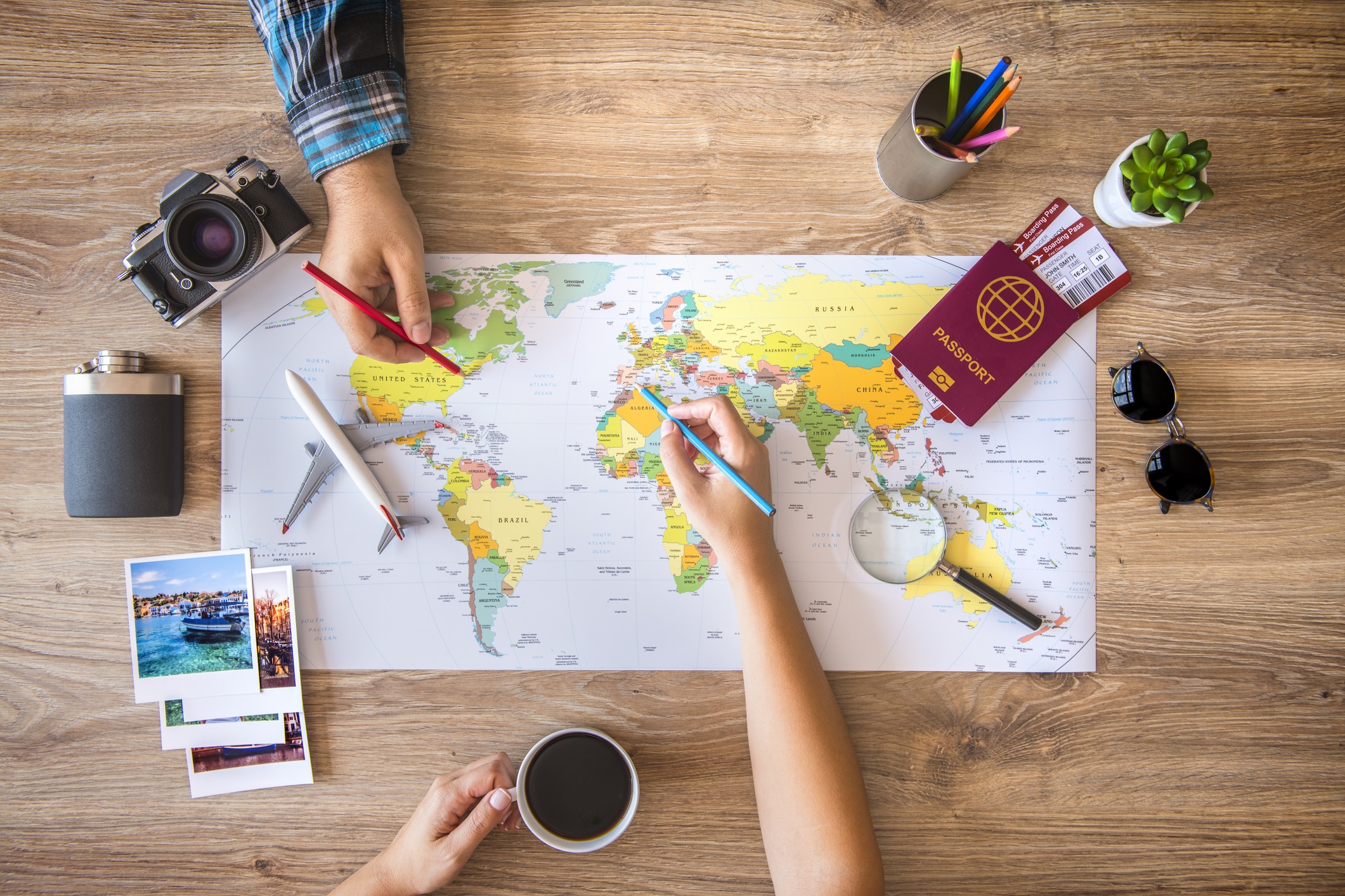 Zwei Personen arbeiten an einer Karte und planen eine Reise; Reiseinformationen auf dem Desktop.