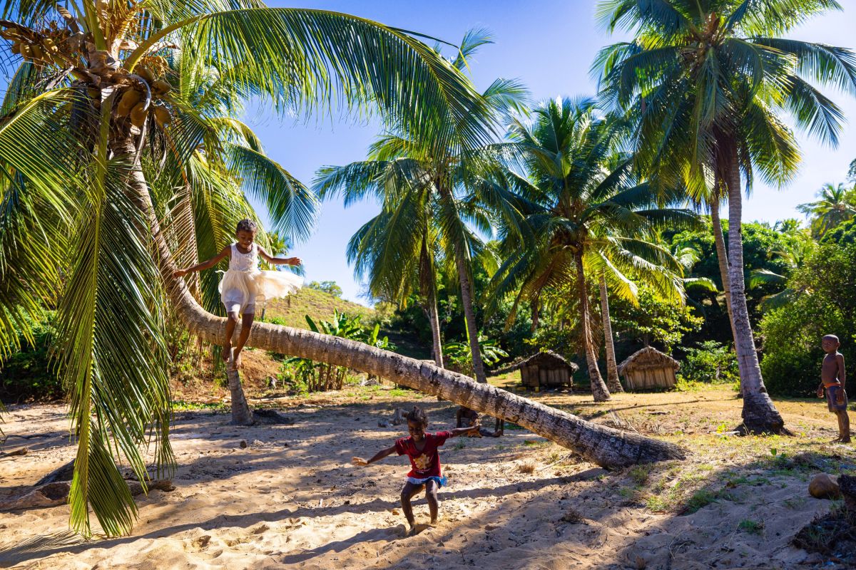 Spielende Kinder am Strand von Madagaskar unter Palmen