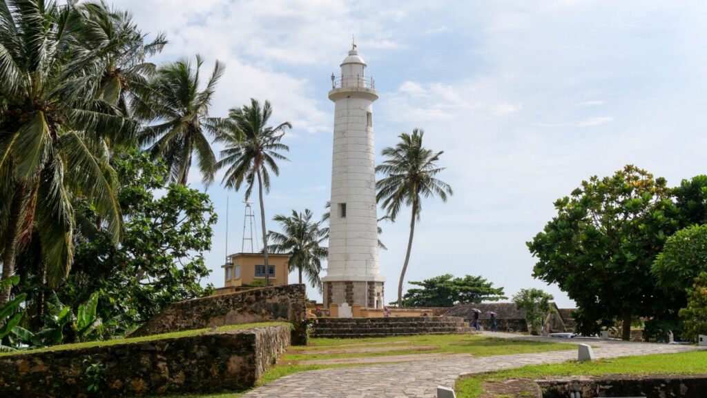 Ältester Leuchtturm in der Hafenstadt Galle, Sri Lanka, umgeben von Palmen.