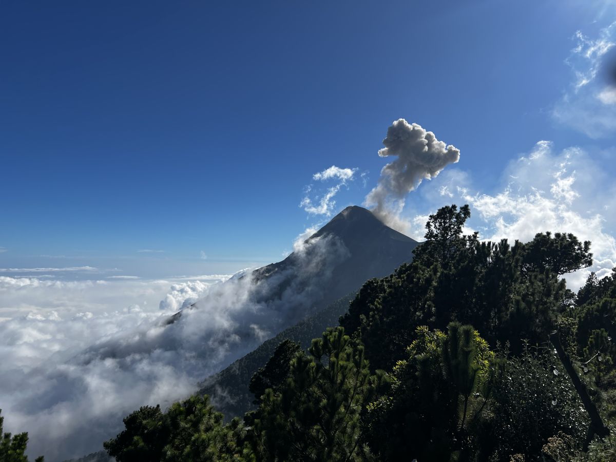 Der Vulkan Fuego in Guatemala spuckt Asche über einer Wolkendecke in den Himmel.