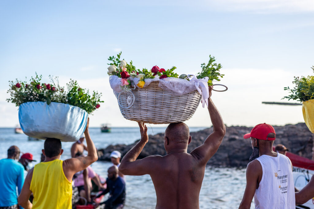 Menschen auf den Kapverden mit Körpen auf dem Kopf und Meer im Hintergrund