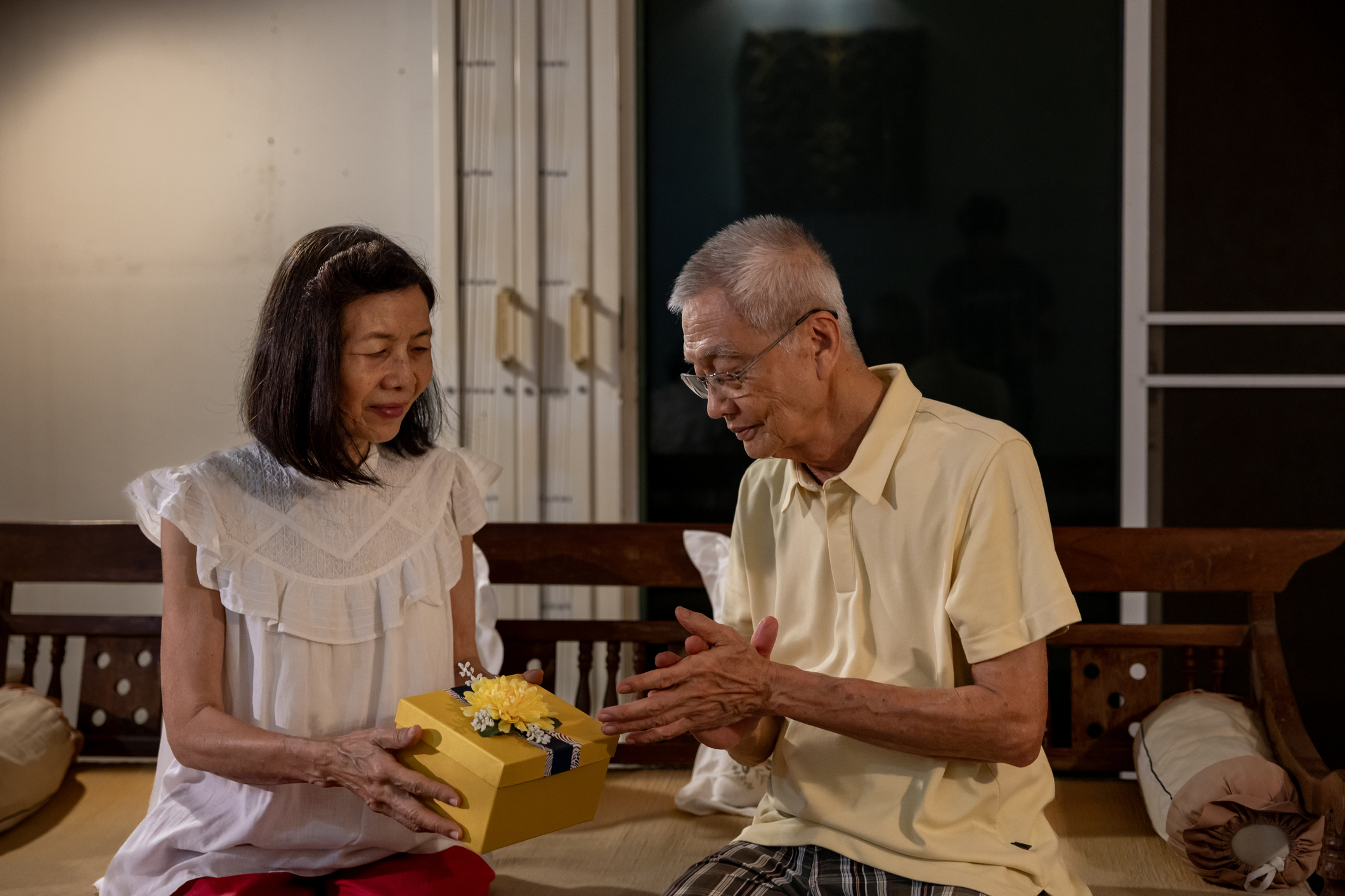 Asiatisches Paar übergibt ein geschenk mit beiden Händen