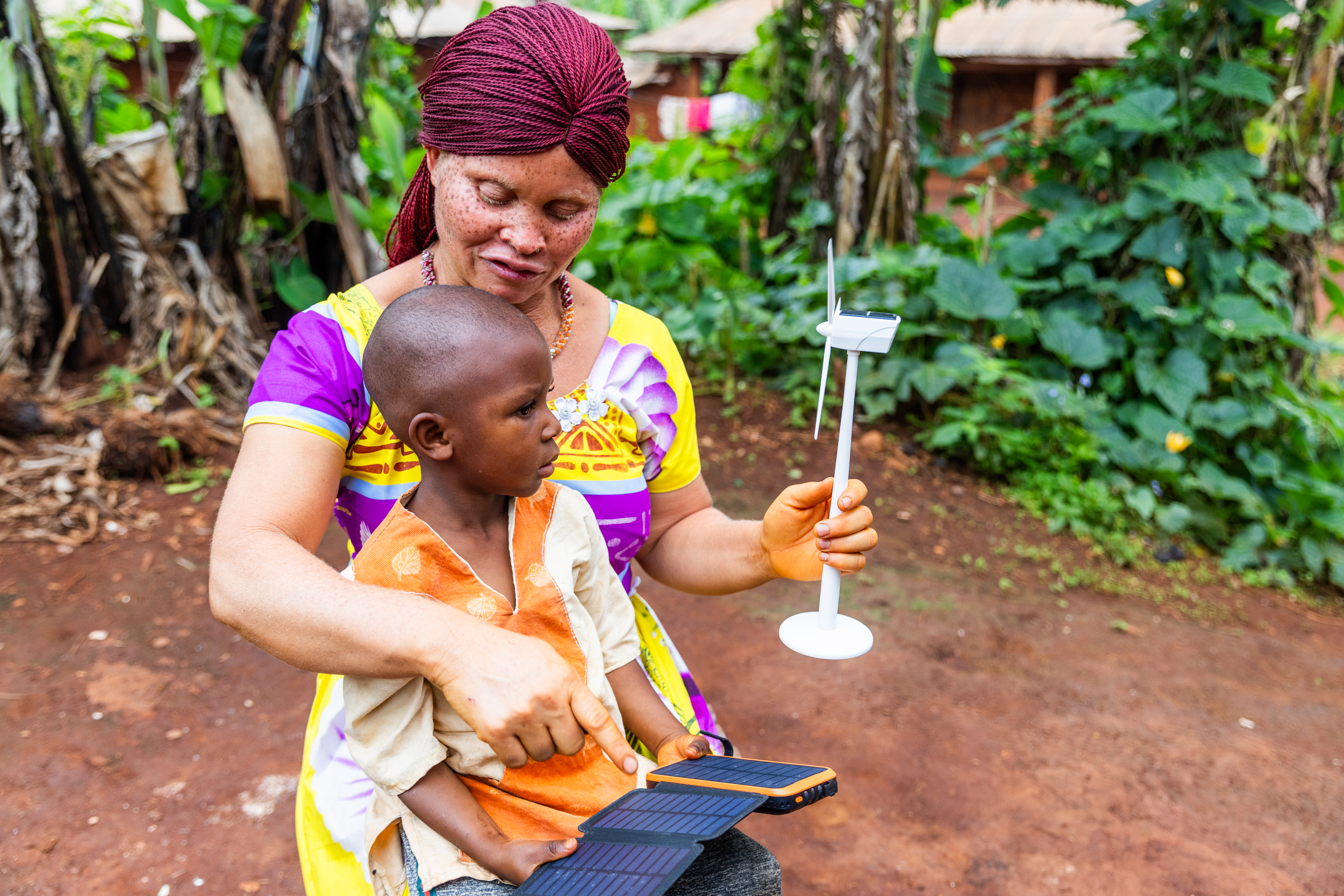 Afrikanische Frau zeigt Kind einen Ventilator der mit Solarpad angetrieben wird
