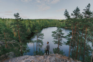 Mann auf Felsen schaut auf Meer und Wald in Finnland