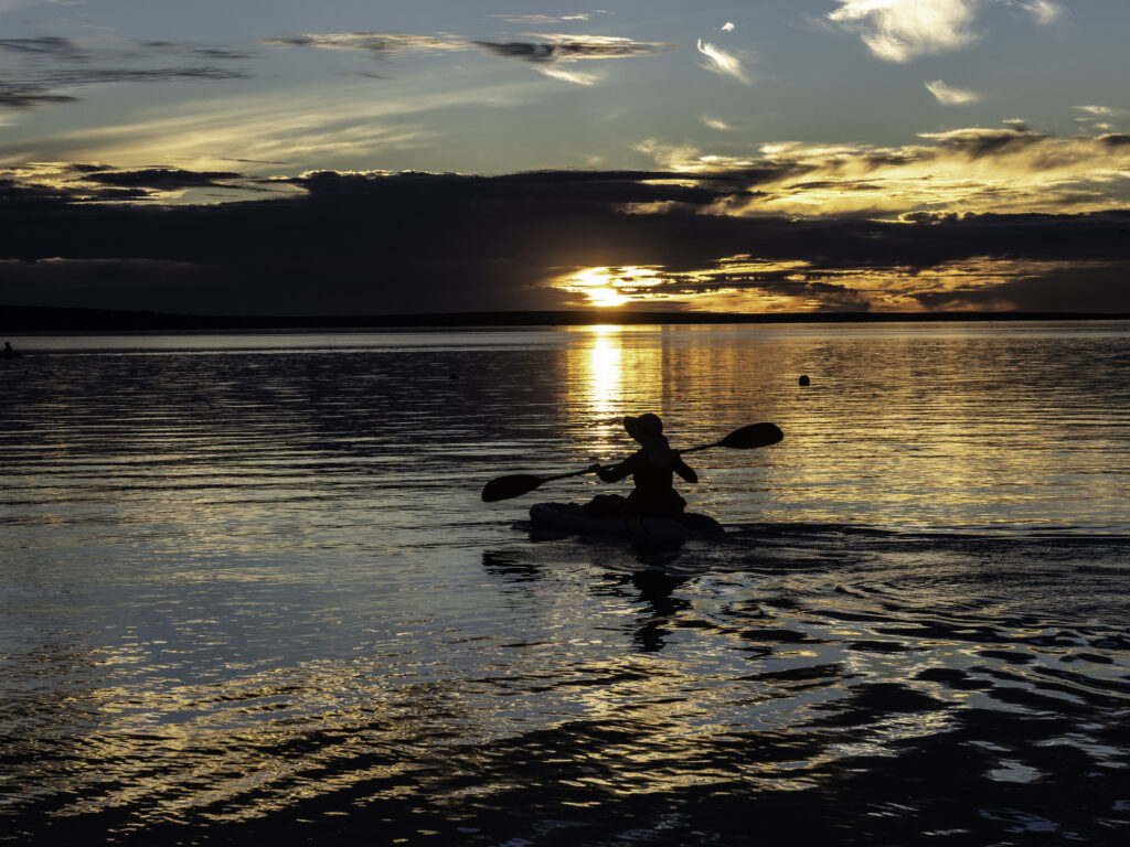 Person in Kajak im Wasser mit Mitternachtssonne