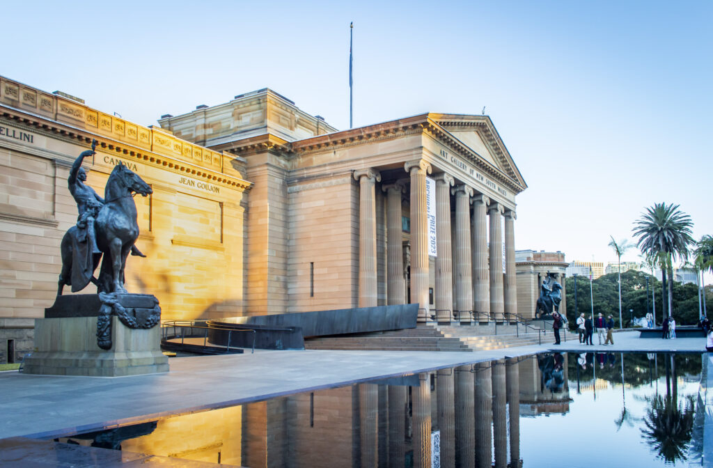 Art Gallery of New South Wales mit stillem Wasser davor, welches das Gebäude und eine Pferdestatue reflektiert