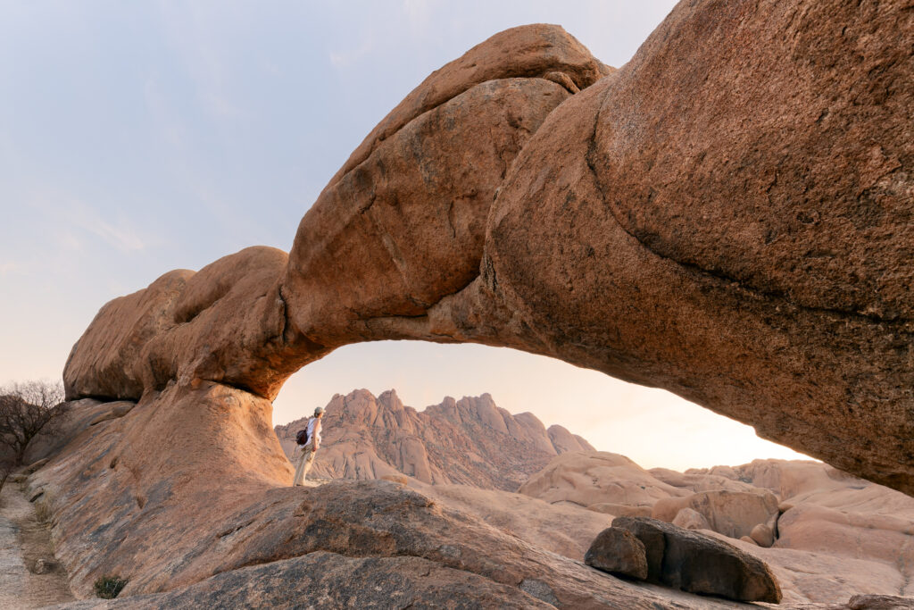 Junges Mädchen in der Gegend um Spitzkoppe mit malerischen Steinbögen und einzigartigen Felsformationen im Damaraland, Namibia