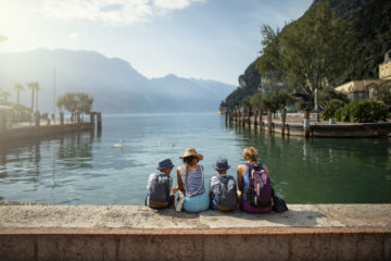 Eine Familie sitzt im Hafen von Riva del Garda und genießt den Blick auf den Gardasee.