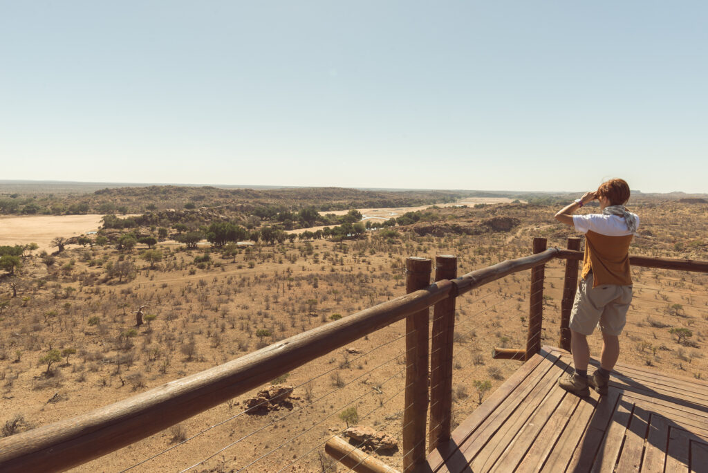 Ein Tourist betrachtet mit einem Fernglas das Panorama vom Aussichtspunkt über dem Mapungubwe-Nationalpark, einem Reiseziel in Südafrika.