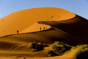 Touristen besteigen die Sossusvlei-Düne im Naukluft-Nationalpark in Namibia.