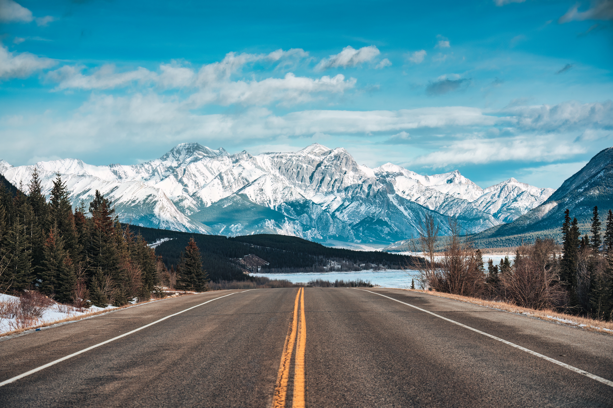 Autoreise auf einer Autobahn durch die schneebedeckten Rocky Mountains im Winter in der Kootenay-Ebene, Alberta, Kanada.