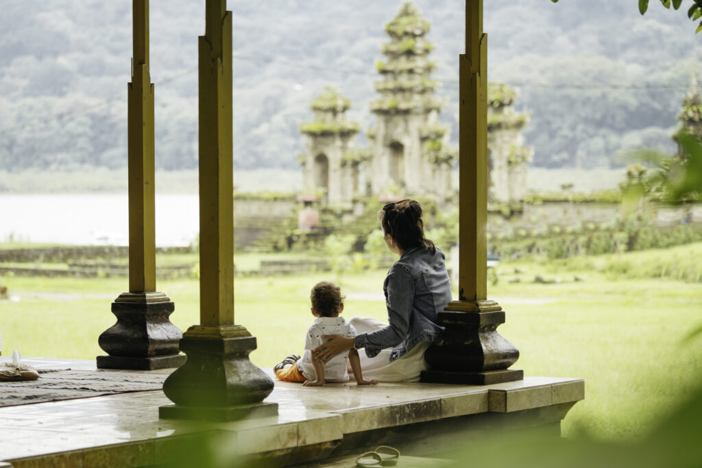 Asien, Indonesien, Bali: Eine asiatische Familie sitzt in einem Pavillon und genießt die Reise vor dem Wassertempel Tamblingan während einer Besichtigungstour.