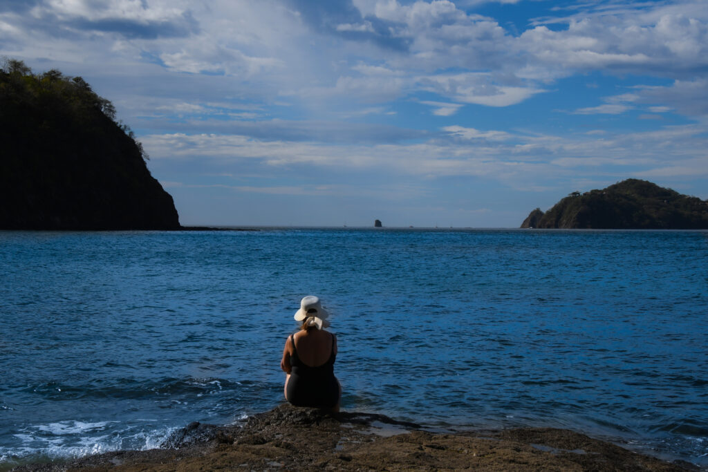 Eine reife Frau sitzt auf einem Felsen in der Culebra-Bucht am Pazifik in Costa Rica.