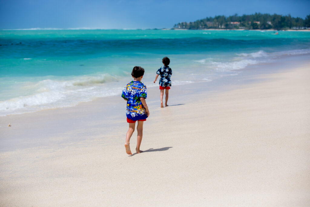 Niedliche Vorschulkinder, Jungen, haben Spaß am Strand. Aufgeregte Kinder spielen mit den Wellen, schwimmen, planschen vergnügt und genießen ihren Familienurlaub auf Mauritius.