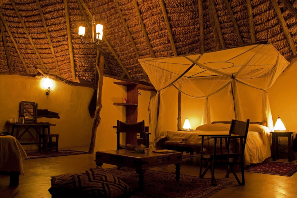 Ein luxuriöses Schlafzimmer in einem Safari-Camp, erleuchtet von Lampenlicht
