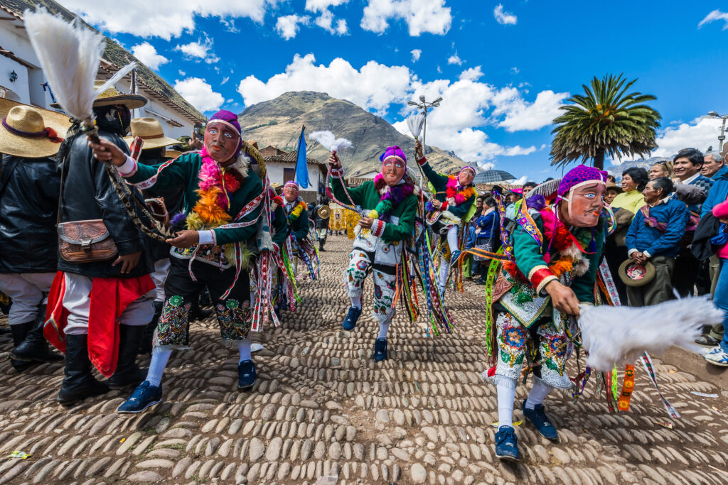 Menschen verkleidet beim Karneval in Peru mit Anden im Hintergrund
