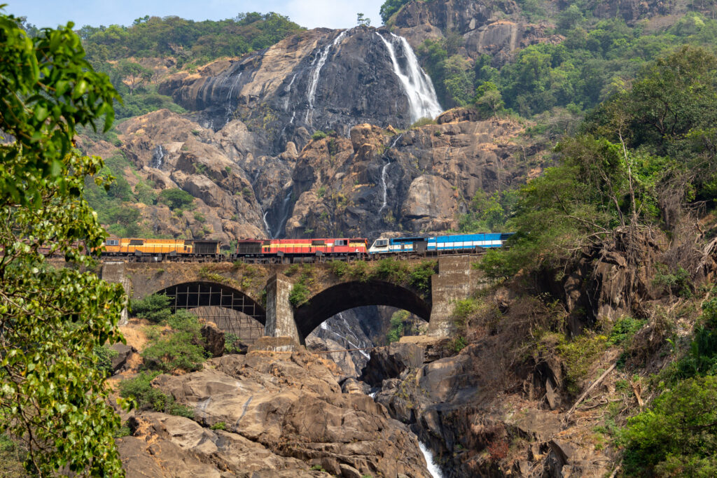 Zug auf der Eisenbahnbrücke vor der Kulisse der Dudhsagar-Wasserfälle