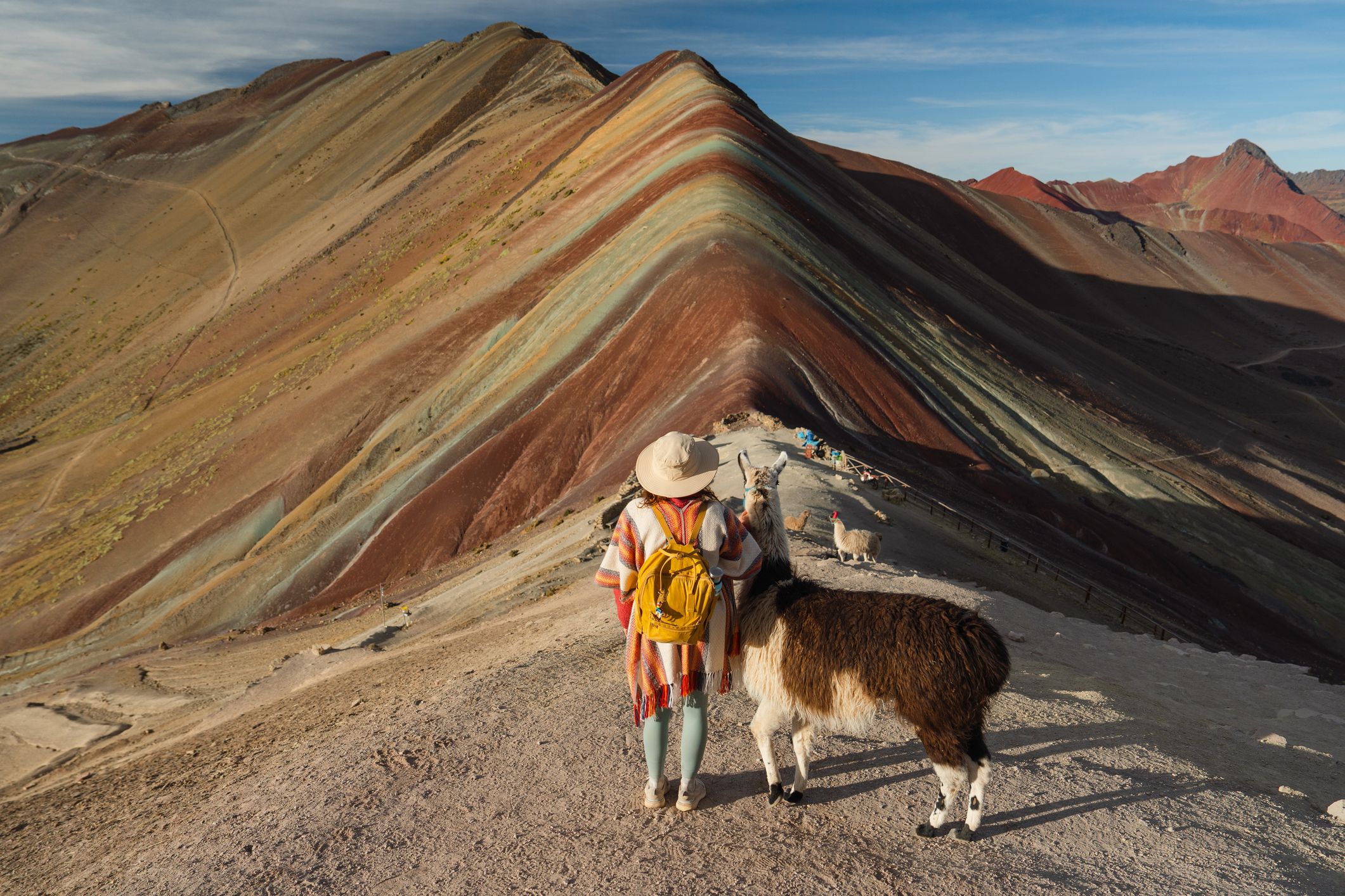 Frau mit Alpakas vor dem Hintergrund des Regenbogenbergs in Peru
