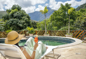 Junge Frau entspannt mit einem Cocktail auf einem Liegestuhl in einer Lodge