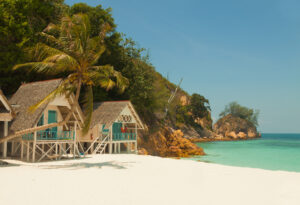 Landschaft eines tropischen Inselstrandes mit perfektem Himmel und schönen Bungalows.