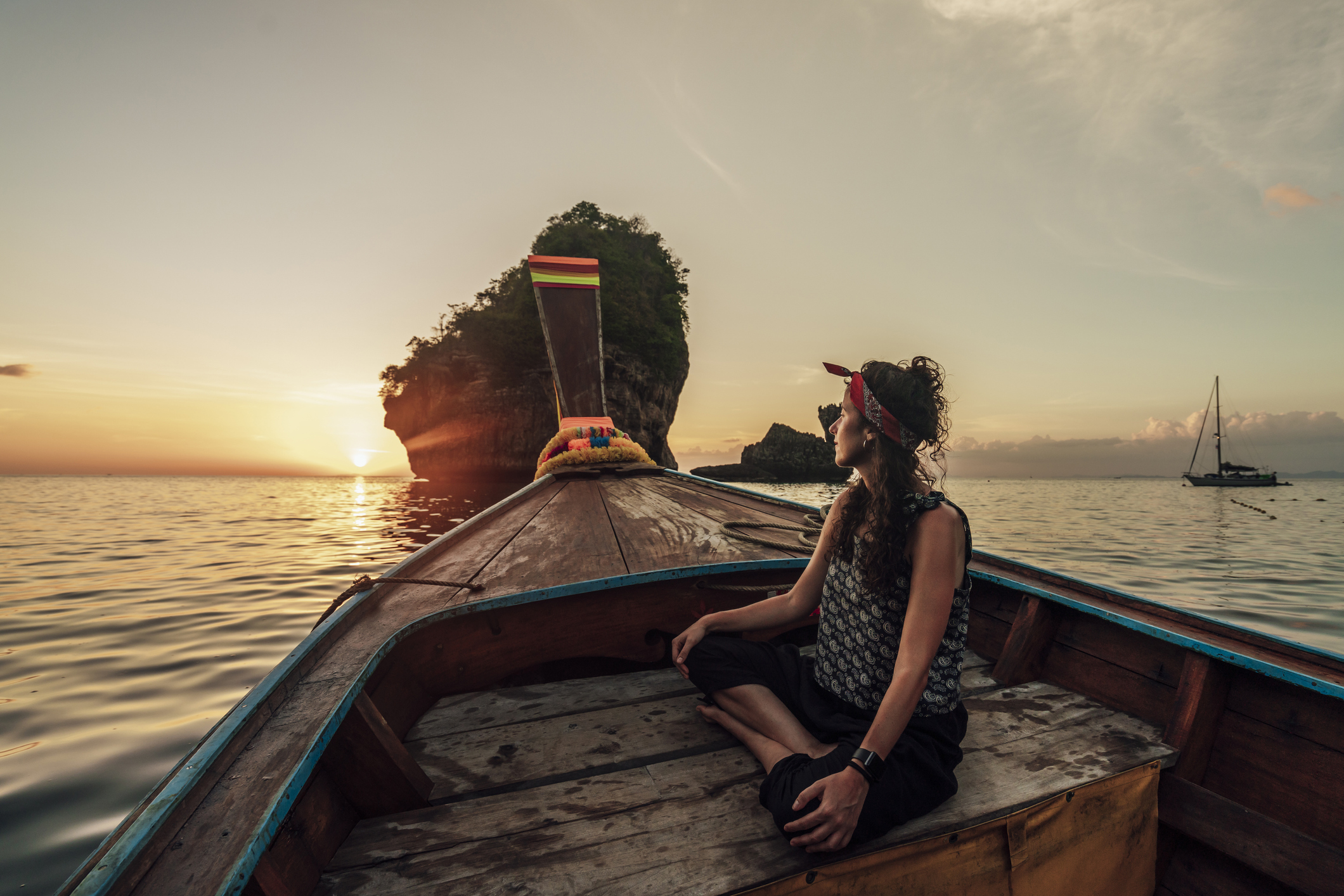 Junge Frau auf einem Longtailboot in Thailand bei Sonnenuntergang