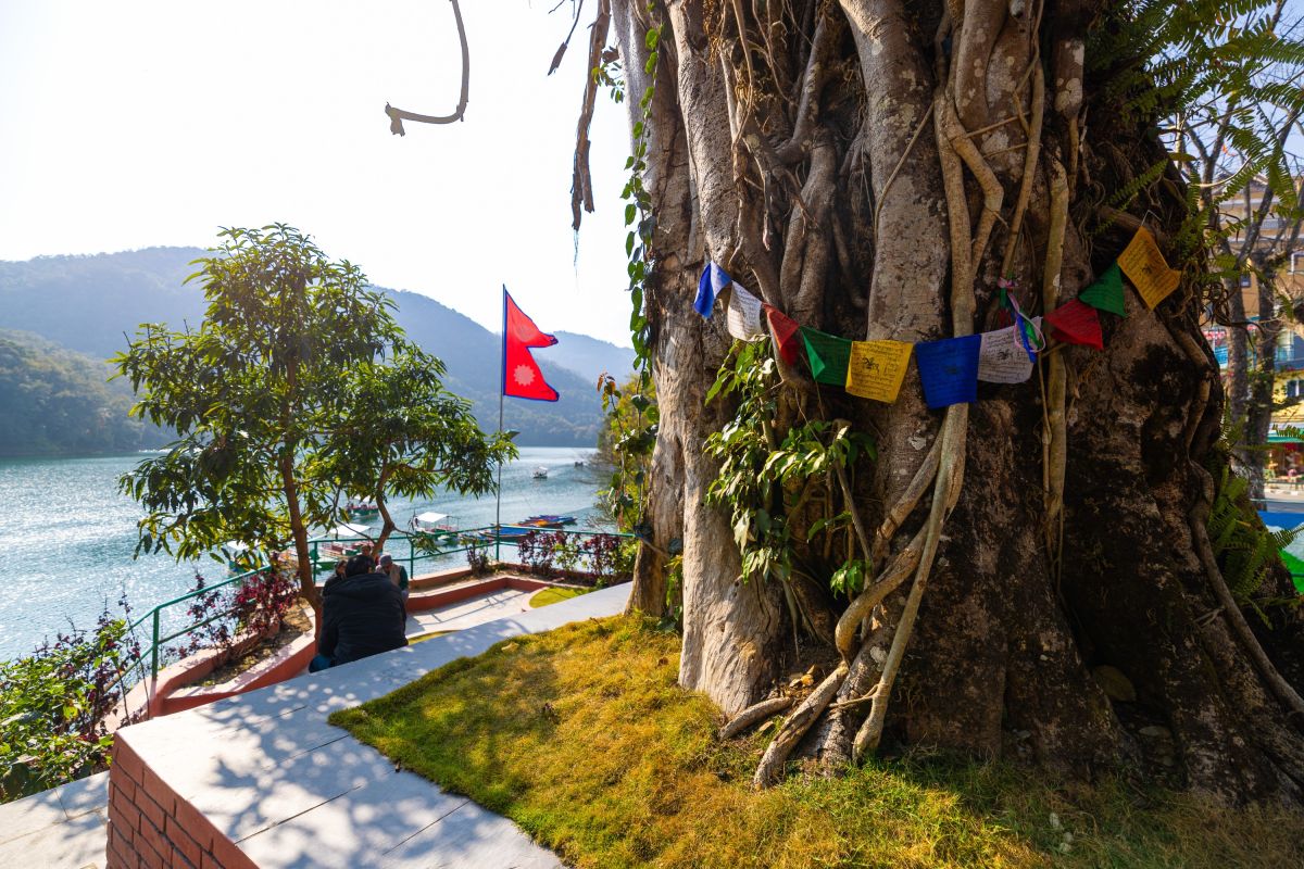 Ufer mit Gebetsfahnen und Blick auf den Phewa-See in Pokhara, Nepal