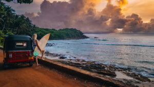 Frau mit Surfboard am Strand von Sri Lanka