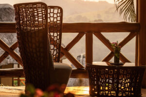 Sitzbereich im Freien mit geflochtenen Stühlen auf dem Balkon bei Sonnenuntergang in Uganda