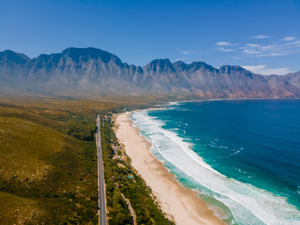 Kogelbay Beach, Westkap, Südafrika. Schroffe Küste mit spektakulären Bergen. Garden Route. Drohnenaufnahme einer Straße in den Bergen direkt am Meer.