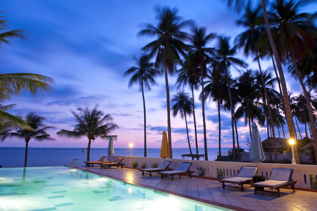 Sonnenuntergangsblick auf einen beleuchteten, von Palmen umgebenen Swimmingpool in Vietnam