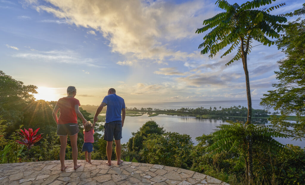 Vater, Mutter und Tochter beobachten den Sonnenaufgang über einer Lagune und dem Pazifik im Corcovado-Nationalpark auf der Osa-Halbinsel in Costa Rica.