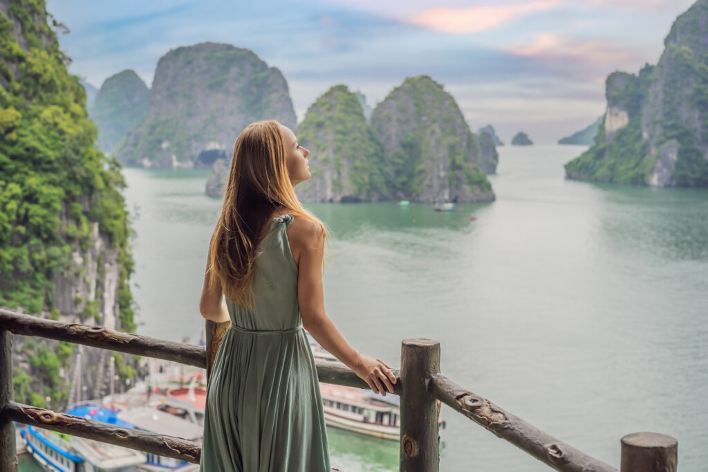 Eine Frau im Kleid schaut auf die Halong-Bucht in Vietnam.