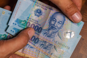 Eine Männerhand hält einen Fächer aus vietnamesischen Dong-Banknoten, der Währung Vietnams.