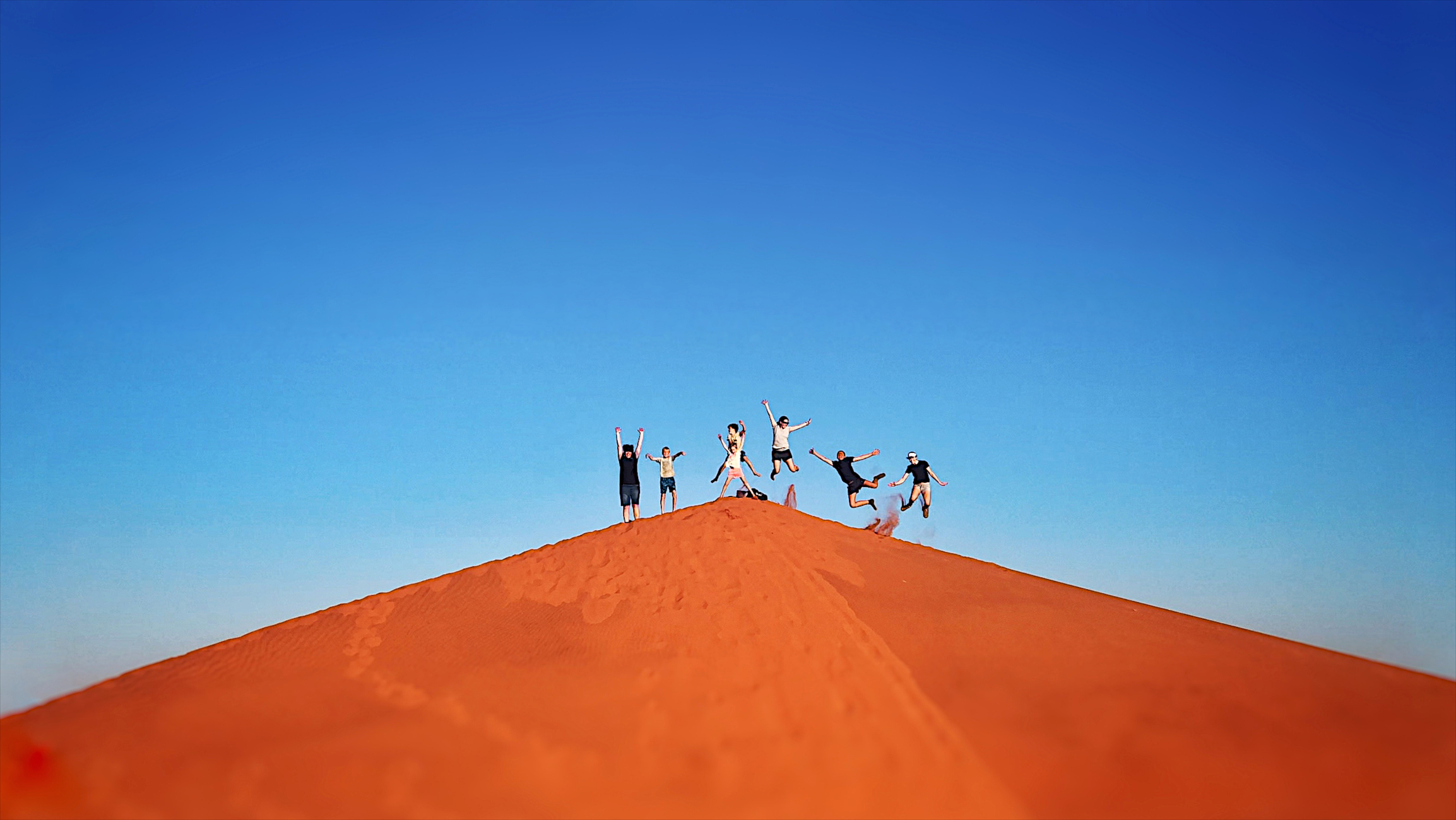 Reisende springen auf roten Sanddünen in Namibia