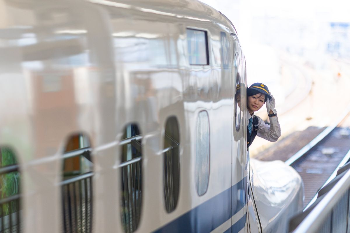 Shinkansen am Bahnsteig in Kyoto mit Zugbegleiterin im Fenster