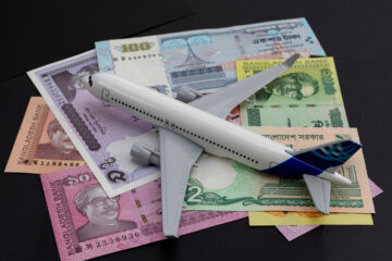 Modellflugzeug auf Geldscheinen als Symbol fuer Reisebudget und Indienplanung
