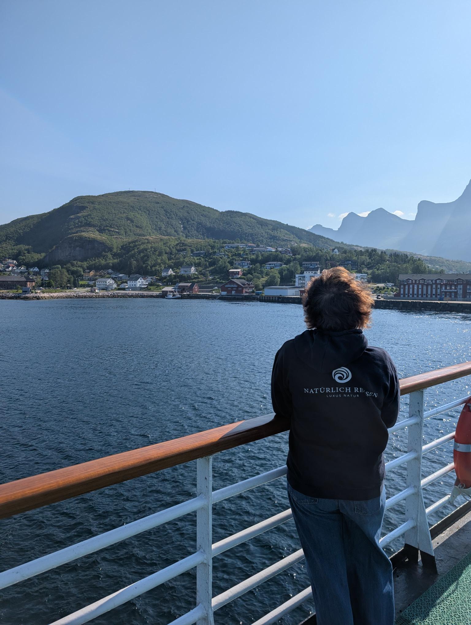 Mitarbeiterin von Natürlich Reisen blickt von einem Schiff auf die norwegische Fjordküste