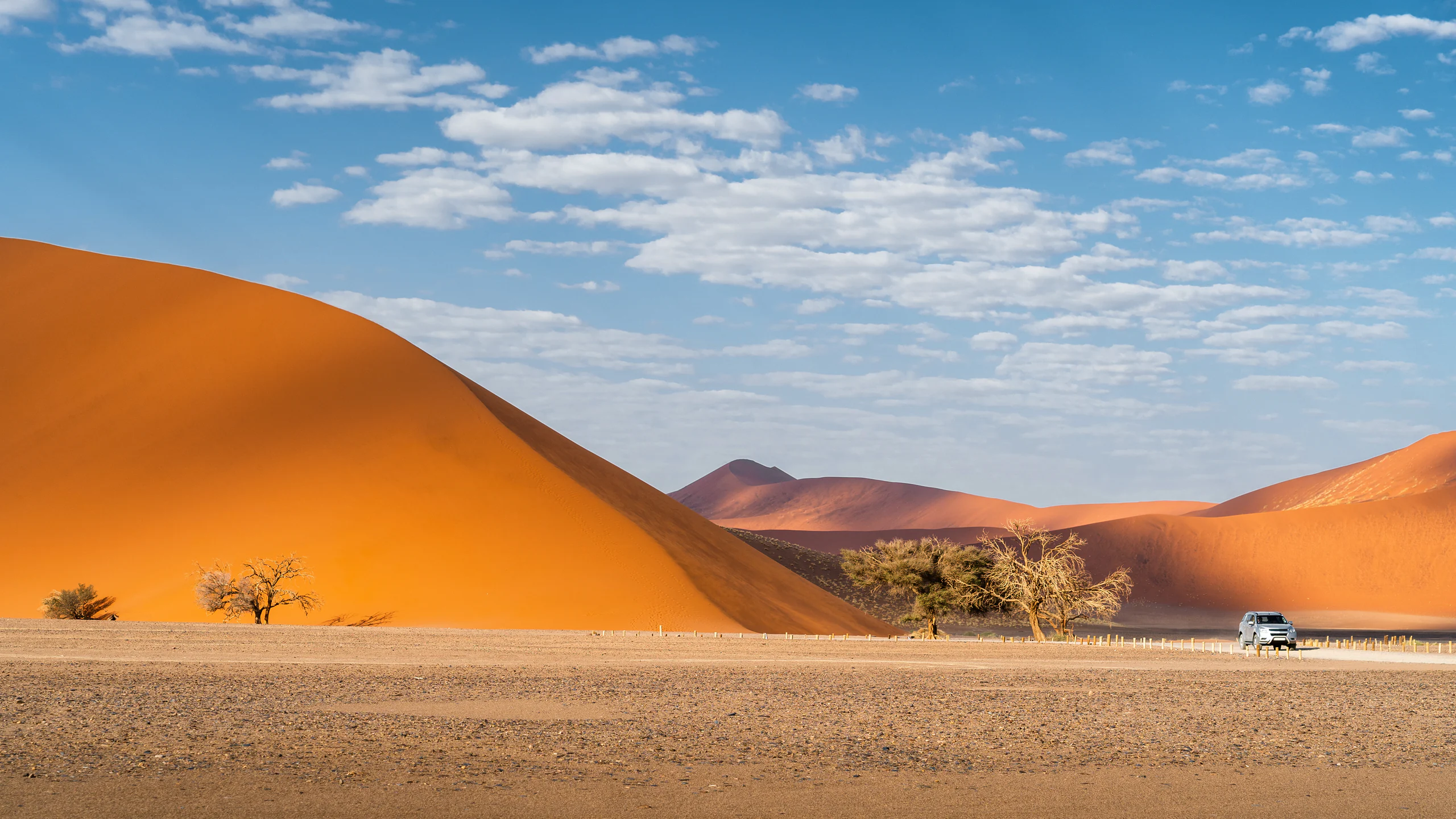Geländewagen vor den roten Dünen von Sossusvlei auf einer Namibia-Rundreise