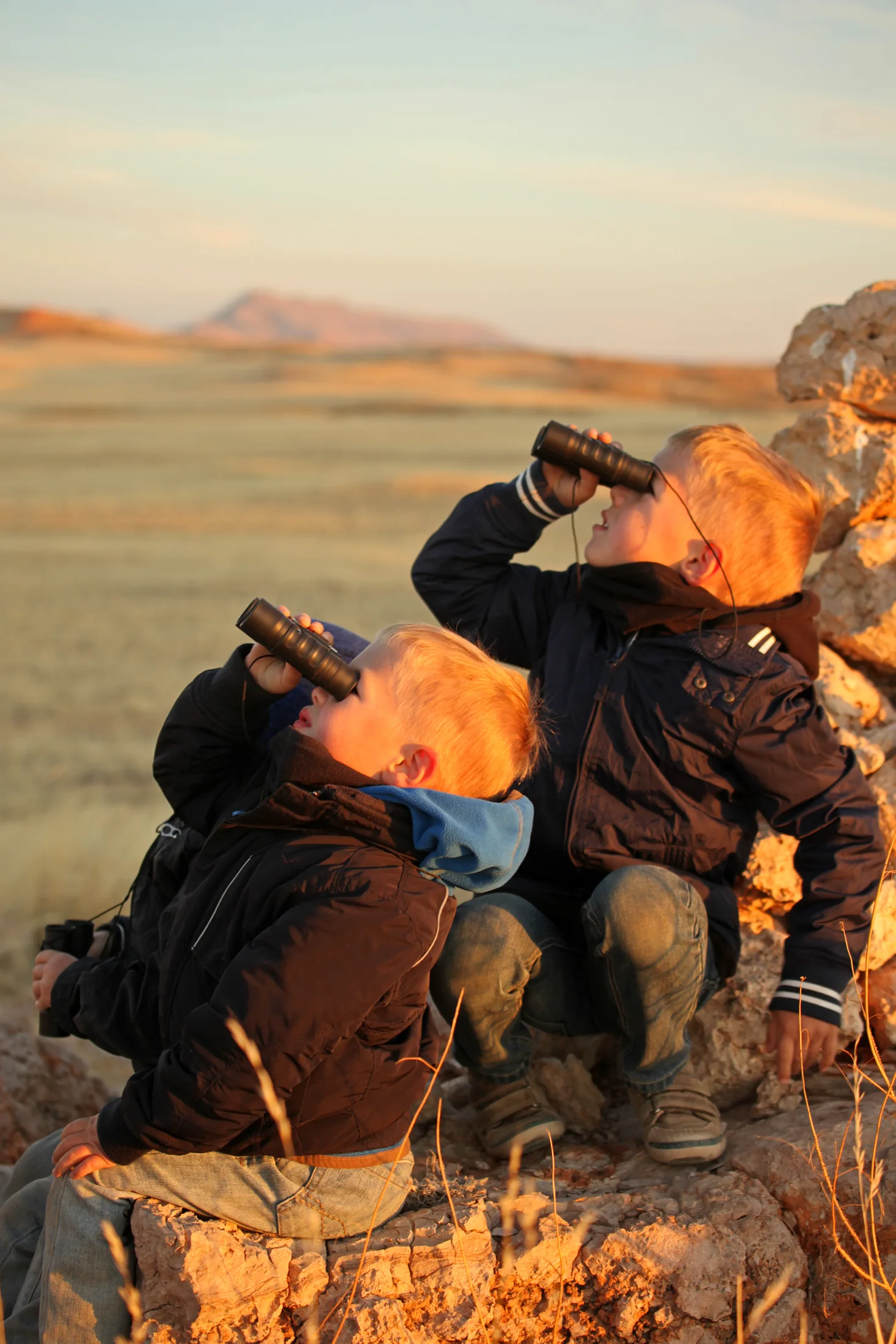 Zwei Kinder beobachten mit Ferngläsern die Landschaft bei einer Safari in Namibia
