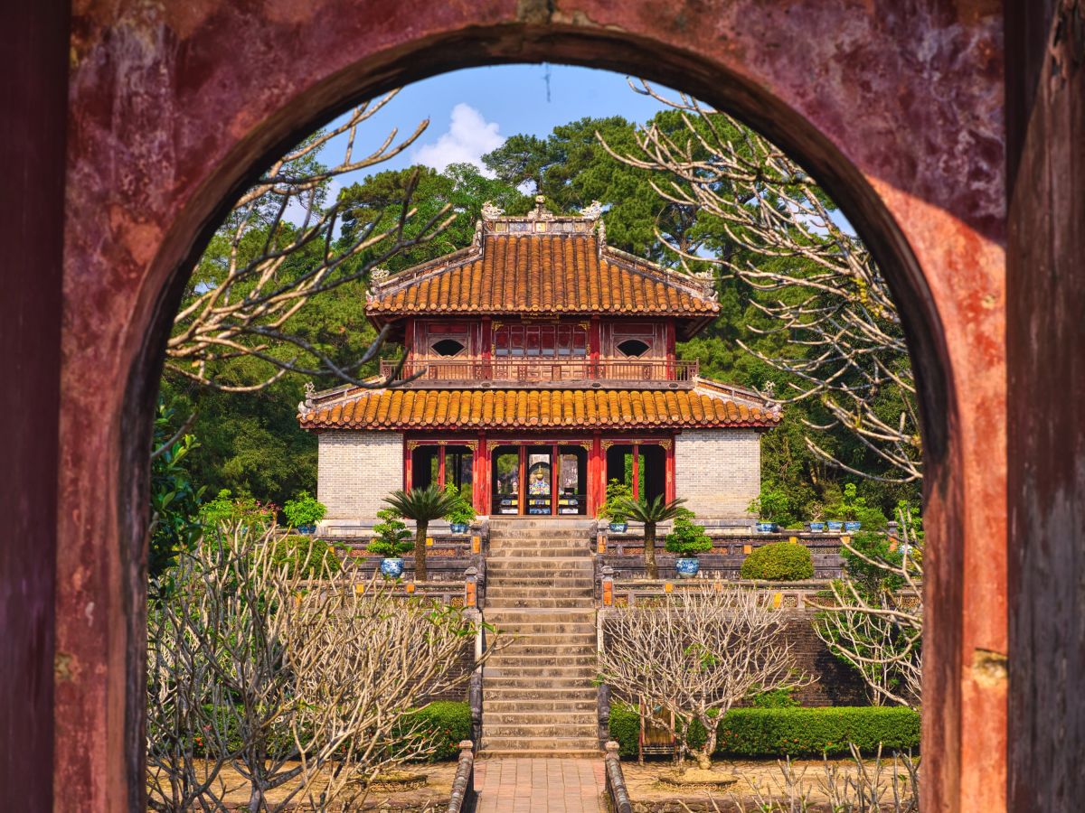 Blick durch ein Rundtor auf die historische Anlage des Minh-Mạng-Grabmals bei Huế, Vietnam