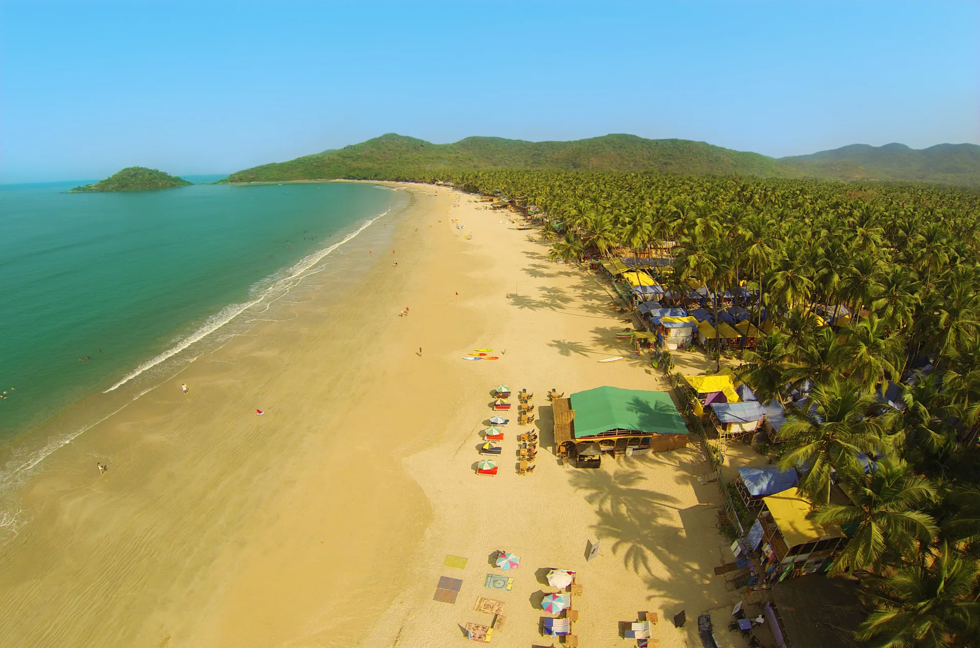 Luftaufnahme der geschwungenen Bucht von Palolem mit Sandstrand und Palmen in Goa