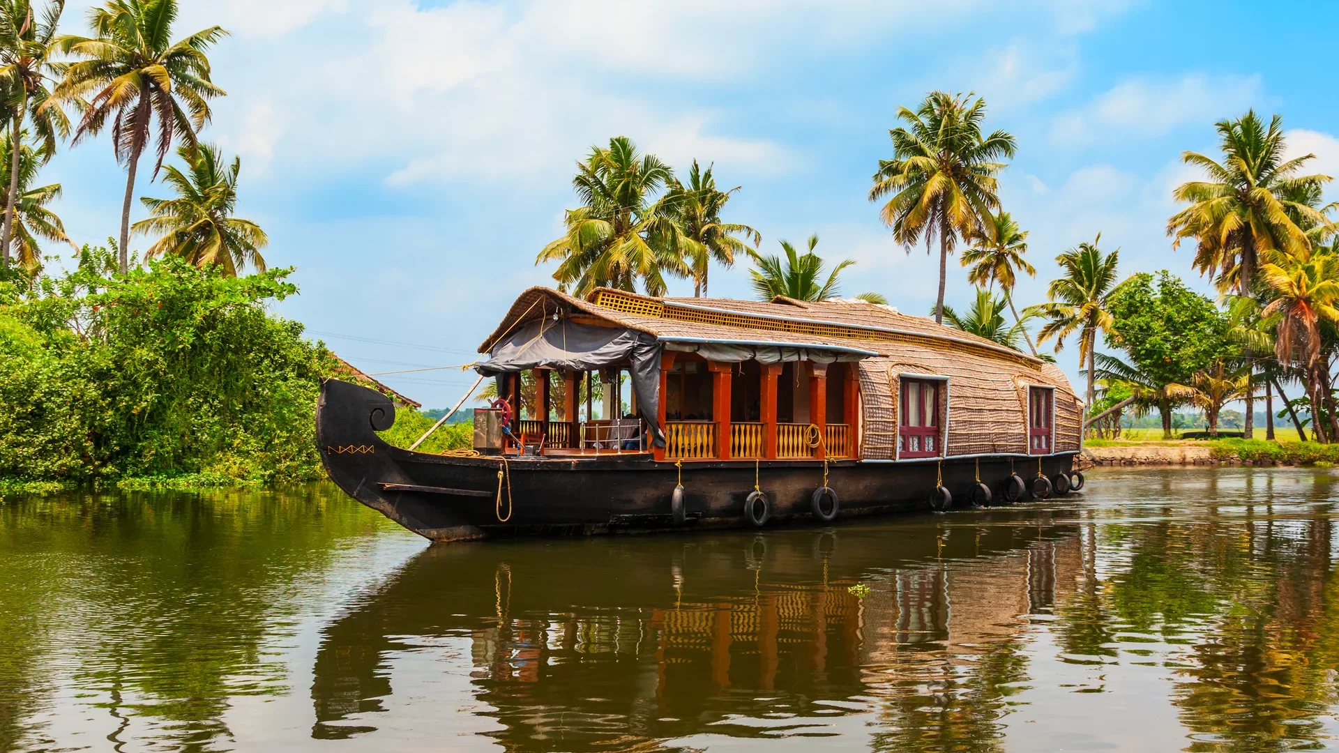 Traditionelles Hausboot vor Palmen auf den Backwaters bei Alappuzha in Kerala