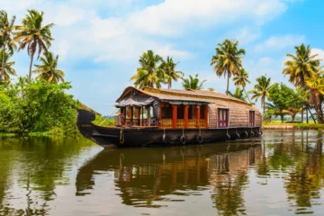 Traditionelles Hausboot vor Palmen auf den Backwaters bei Alappuzha in Kerala